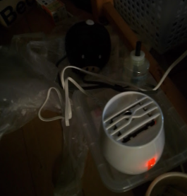 暗い部屋にベープが置かれていて、電源スイッチが赤色に点灯している。