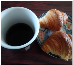 コーヒーの湯飲みの右側に2個のクロワッサン.